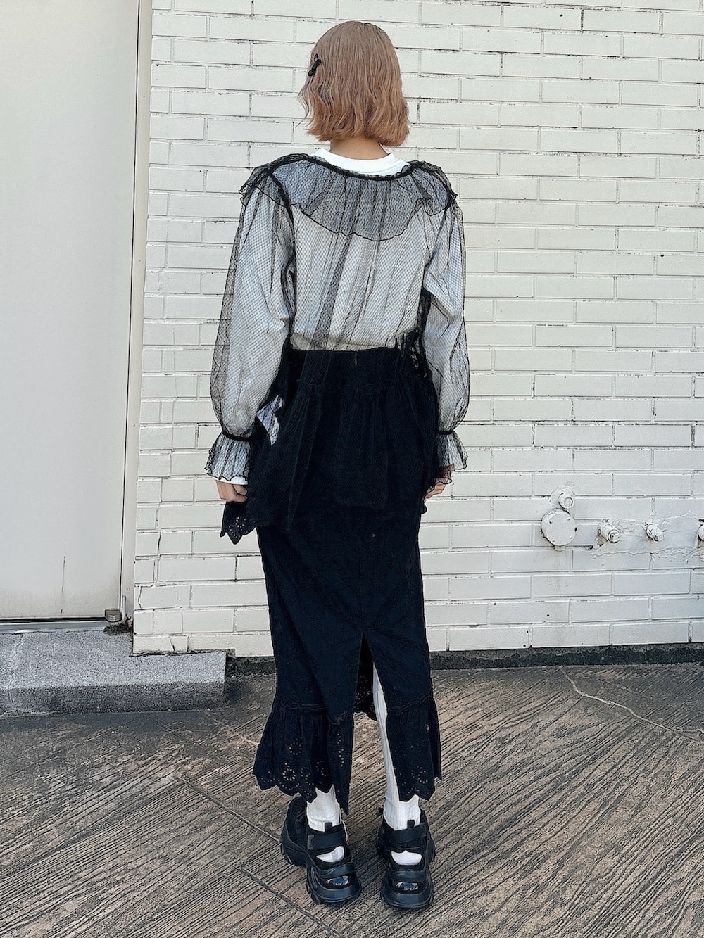 ブラック系のスカート、ブラック系のスニーカー、ホワイト系のTシャツ/カットソーを着用したレディースの春コーディネートの2枚目の写真