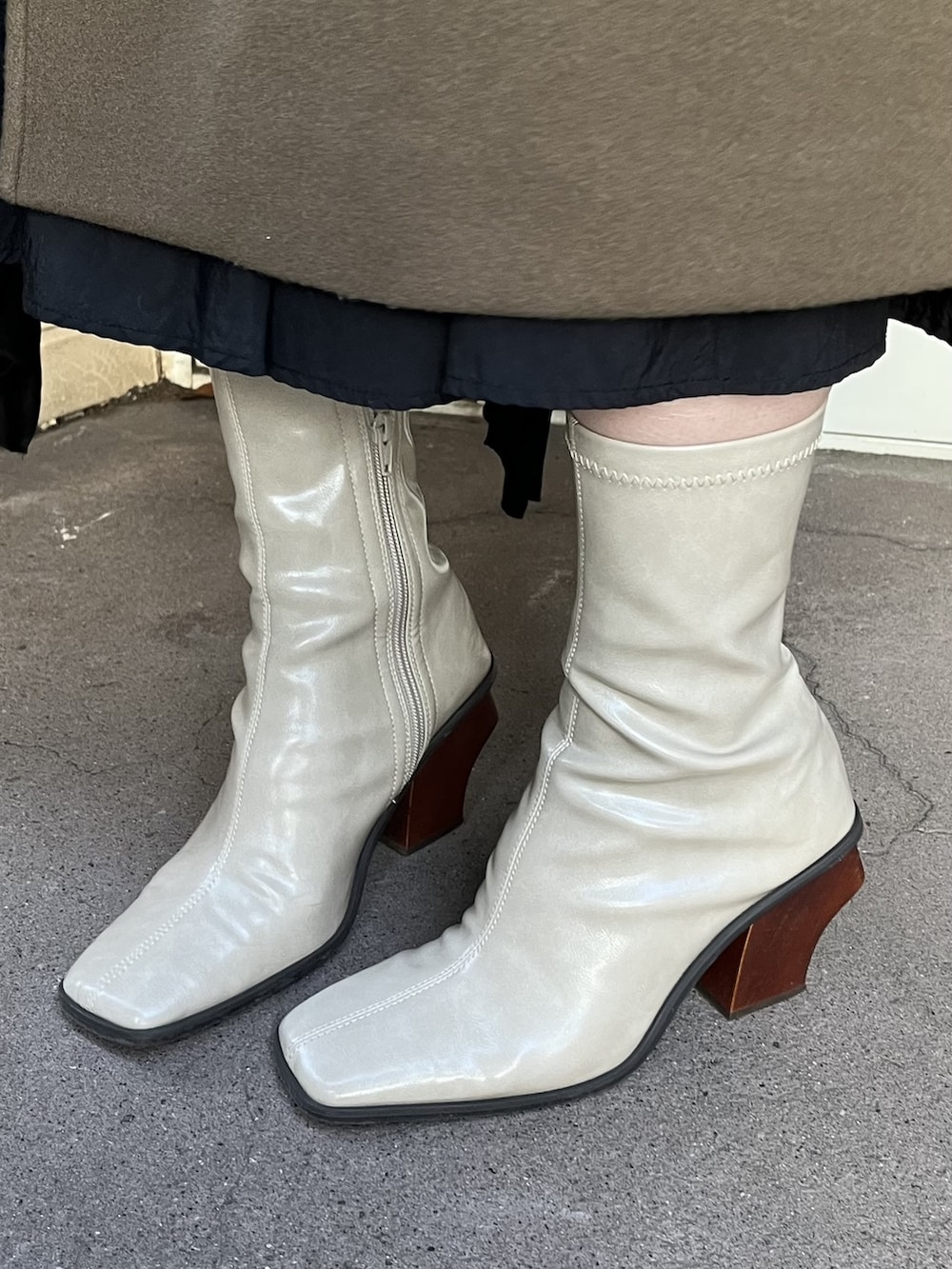 グリーン系のステンカラーコート、ブラック系のスカート、ベージュ系のブーツを着用したレディースの冬コーディネートの4枚目の写真