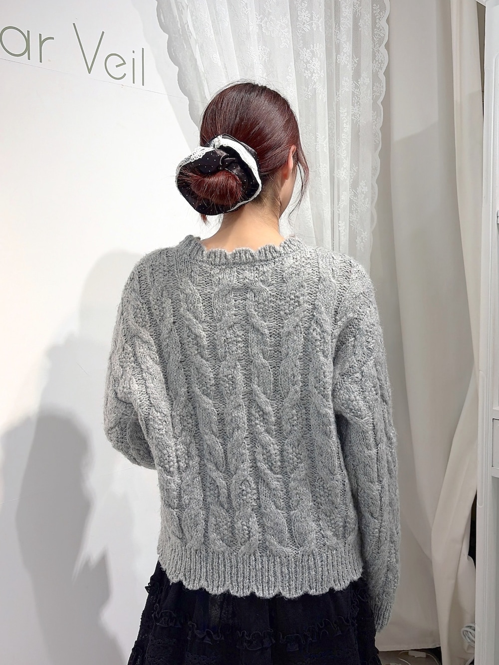 グレー系のニット/セーター、ホワイト系のショルダーバッグ、ブラック系のスカートを着用したレディースの秋コーディネートの5枚目の写真