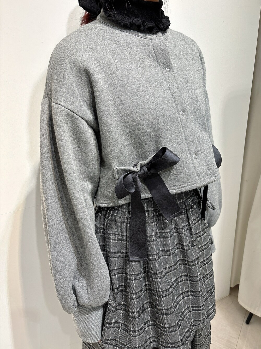 グレー系のスカート、ブラック系のスニーカー、グレー系のカーディガン/ボレロを着用したレディースの冬コーディネートの3枚目の写真