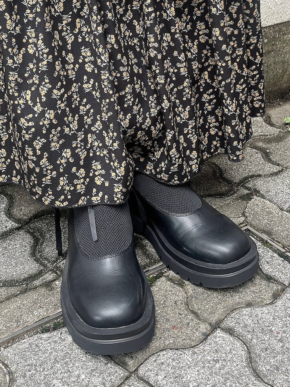 グリーン系のスウェット、ブラック系のスカート、ブラック系のブーツを着用したレディースの秋コーディネートの5枚目の写真