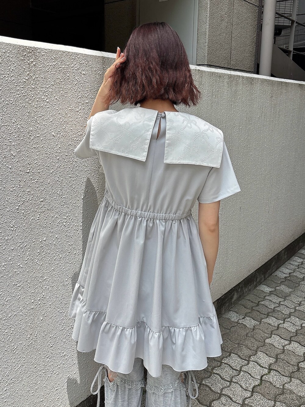 ブルー系のワンピース、グレー系のスウェットパンツ、ホワイト系のスニーカーを着用したレディースの春コーディネートの4枚目の写真