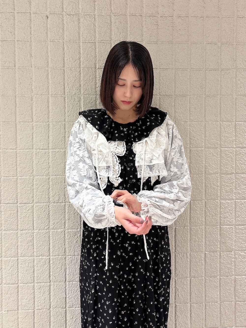 ブラック系のワンピース、ホワイト系のカーディガン/ボレロ、ブラック系のスニーカーを着用したレディースの冬コーディネートの3枚目の写真