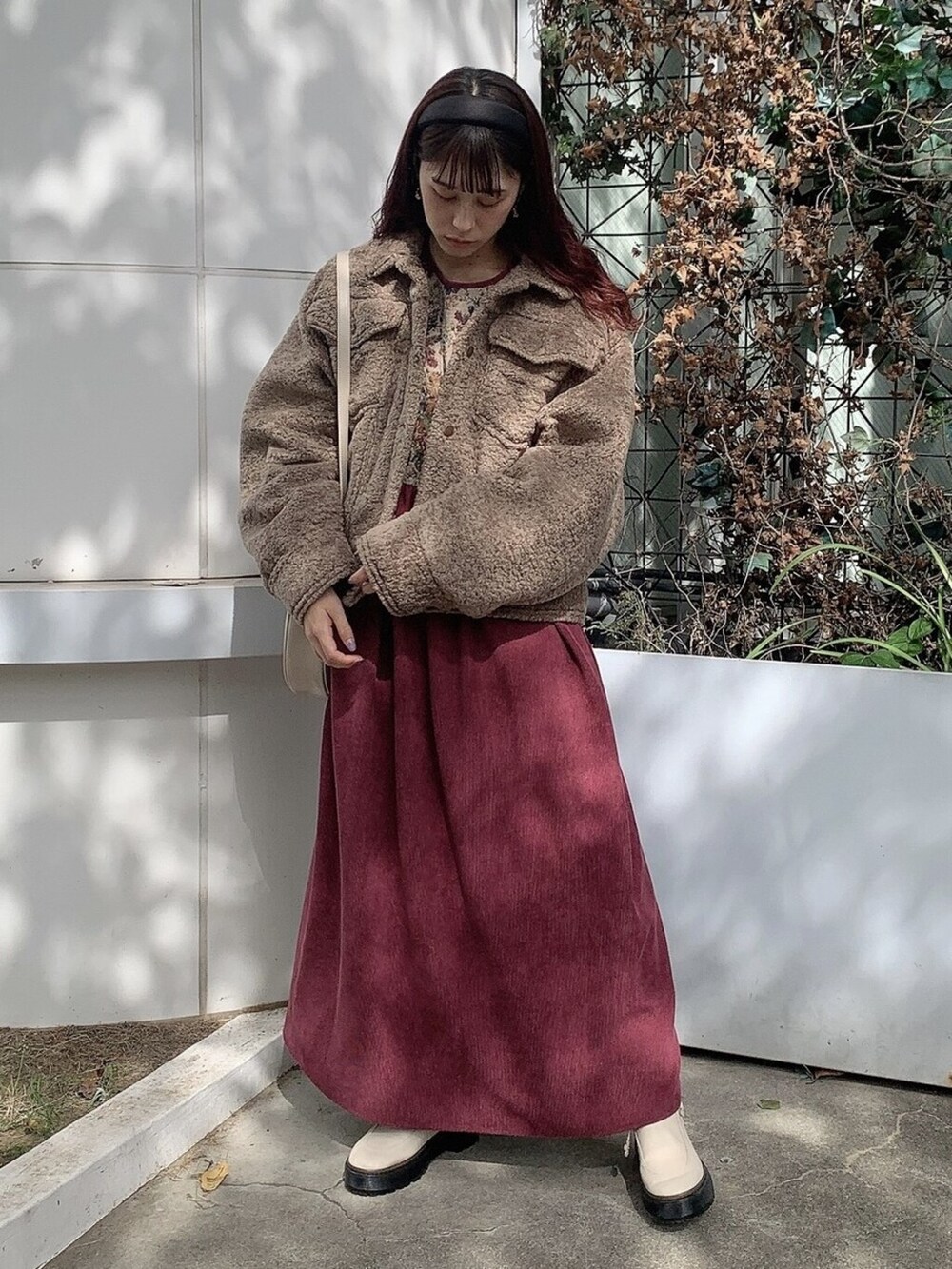 ブラウン系のカバーオール、ホワイト系のブーツ、ホワイト系のショルダーバッグを着用したレディースの秋コーディネートの2枚目の写真