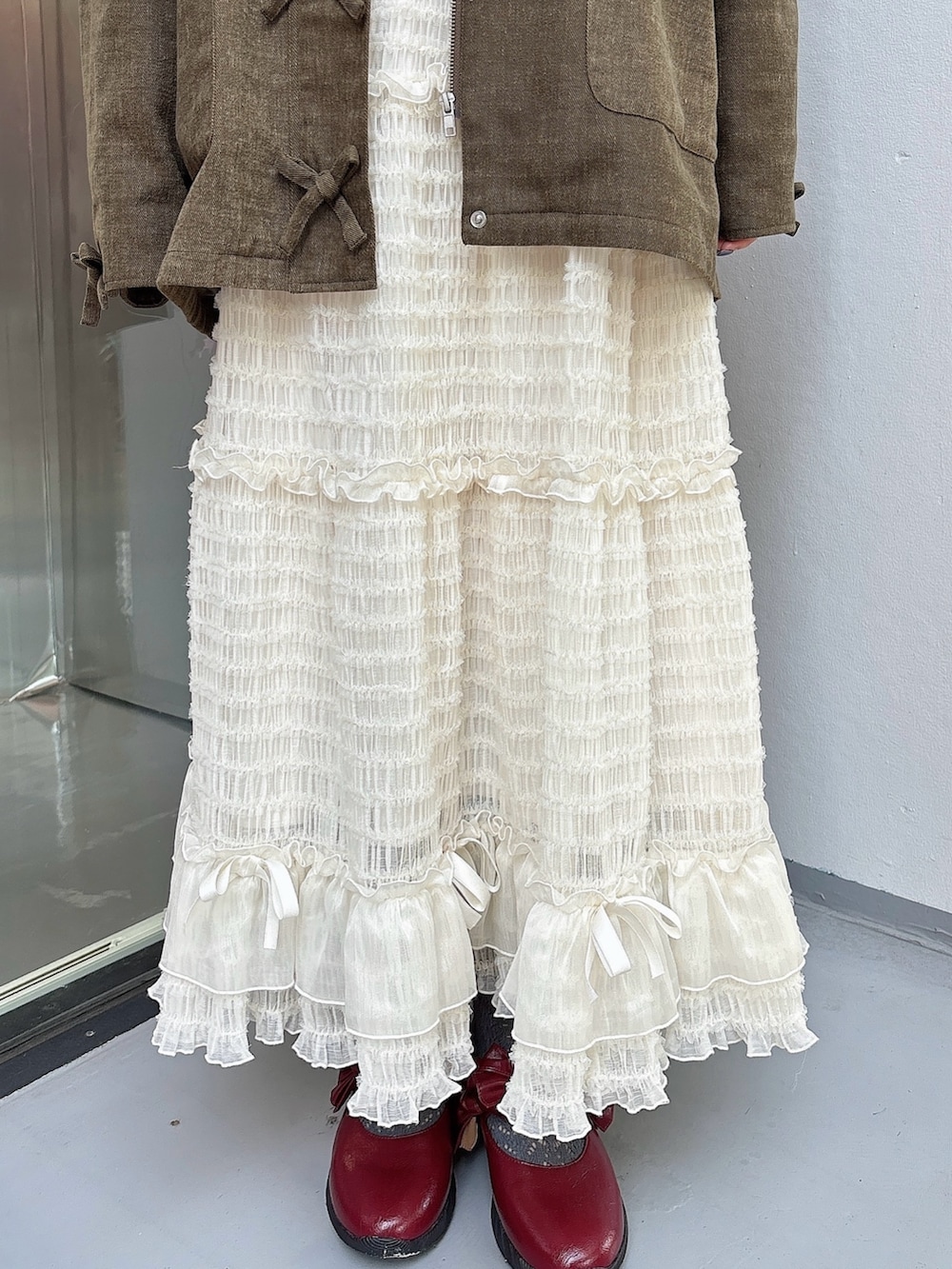 ホワイト系のスカート、ブラウン系のブルゾン、ベージュ系のTシャツ/カットソーを着用したレディースの夏コーディネートの6枚目の写真