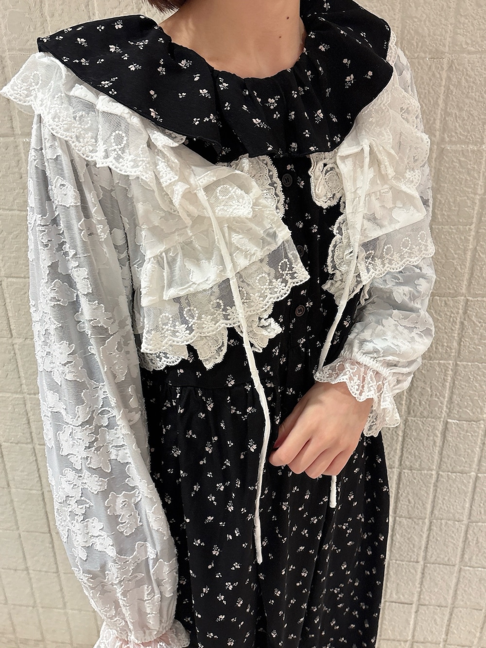 ブラック系のワンピース、ホワイト系のカーディガン/ボレロ、ブラック系のスニーカーを着用したレディースの冬コーディネートの5枚目の写真