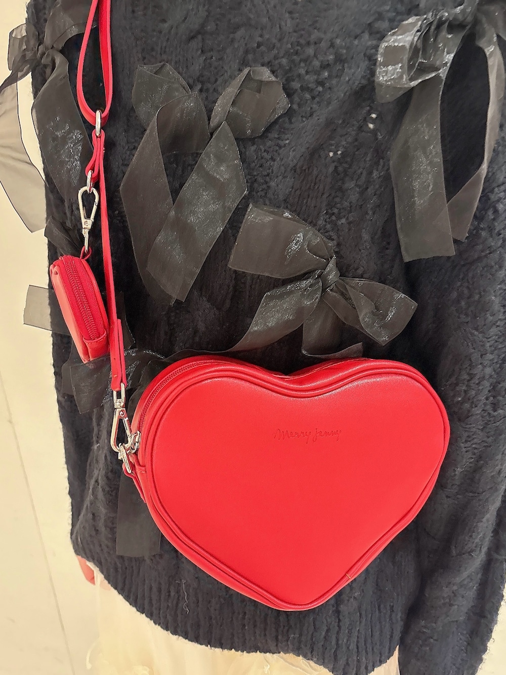 ブラック系のニット/セーター、レッド系のショルダーバッグ、ホワイト系のスカートを着用したレディースの冬コーディネートの5枚目の写真