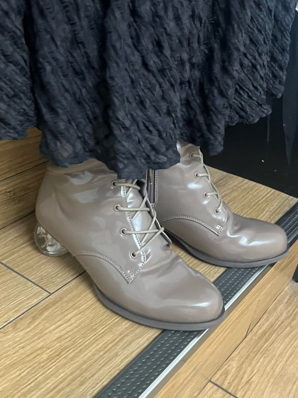 ブラック系のスカート、ベージュ系のブーツ、ブラック系のその他アウターを着用したレディースの冬コーディネートの3枚目の写真