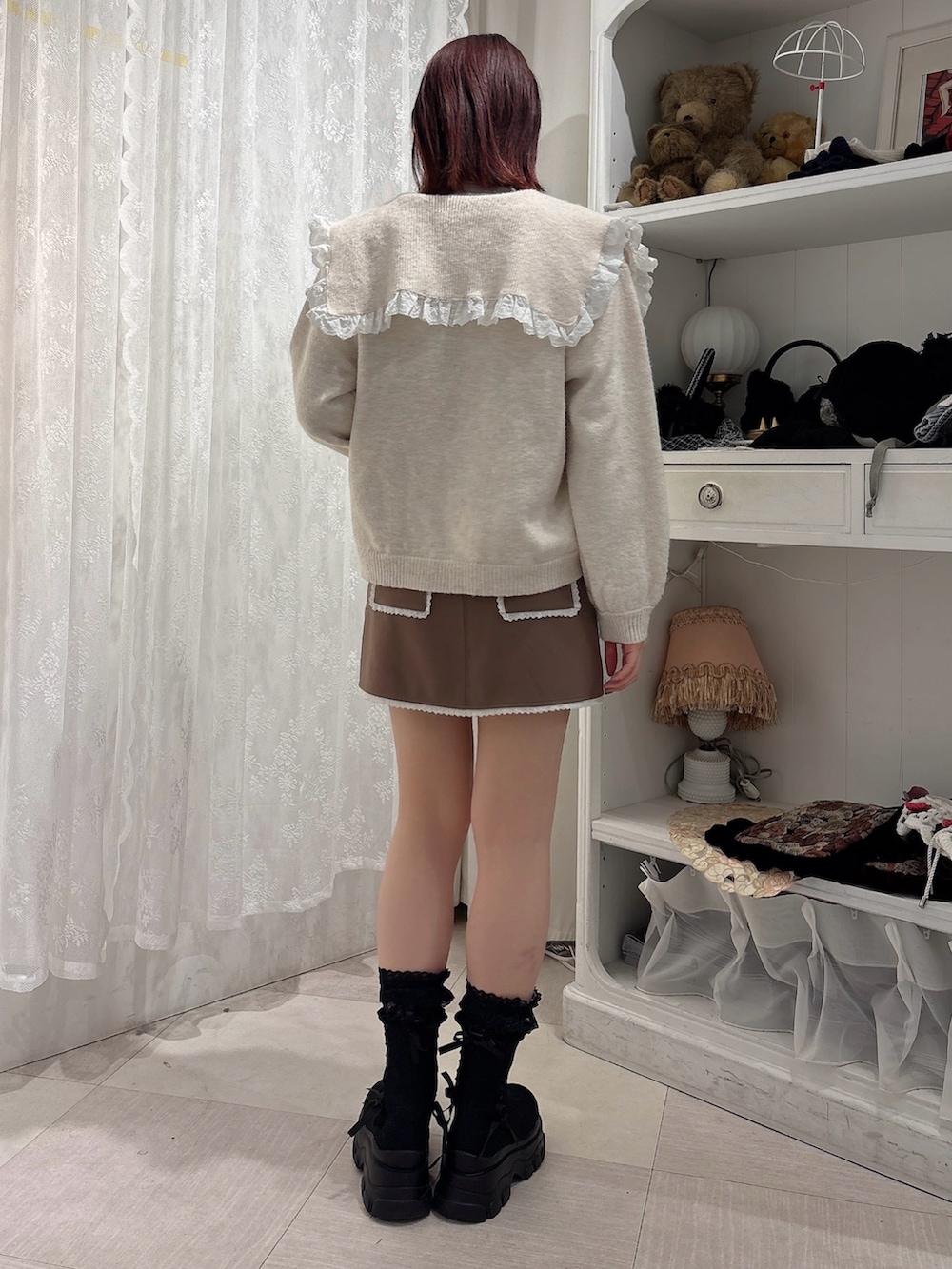 ブラウン系のスカート、ブラック系のブーツ、ホワイト系のカーディガン/ボレロを着用したレディースの秋コーディネートの2枚目の写真