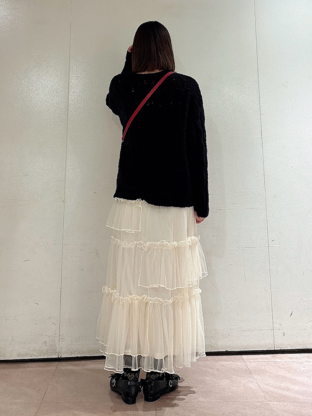 ブラック系のニット/セーター、レッド系のショルダーバッグ、ホワイト系のスカートを着用したレディースの冬コーディネートの2枚目の写真