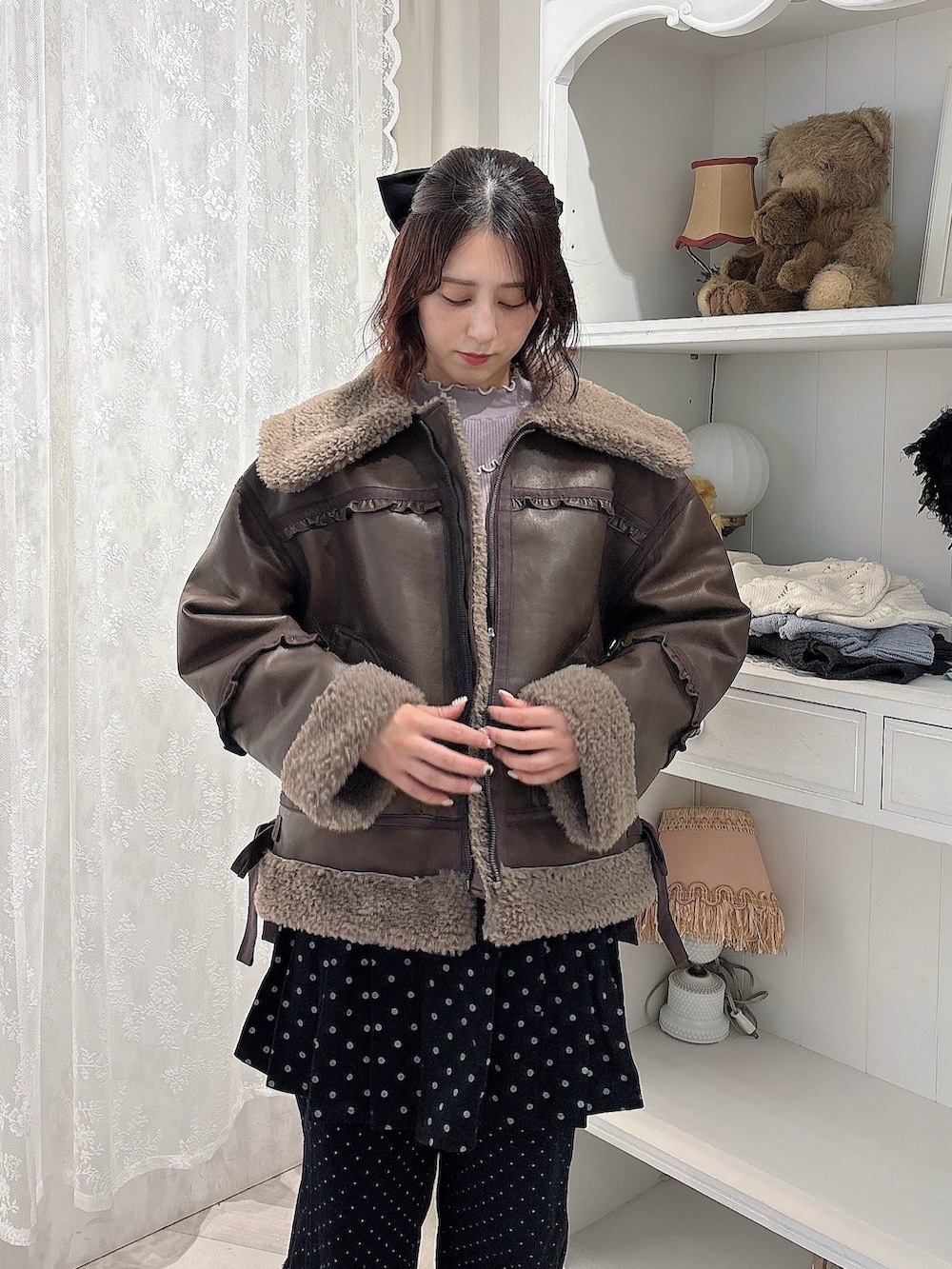 ブラウン系のムートンコート、パープル系のニット/セーター、ブラック系のスカートを着用したレディースの秋コーディネートの3枚目の写真