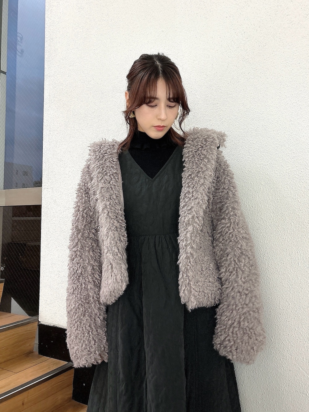 ブラック系のワンピース、ブラック系のパンプス、パープル系のダウンジャケット/コートを着用したレディースの冬コーディネートの2枚目の写真