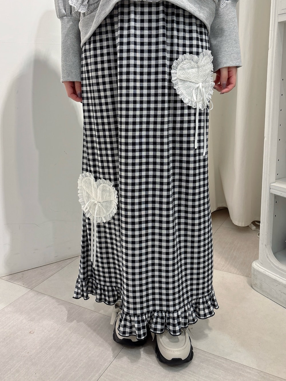 グレー系のパーカー、ブラック系のスカート、ホワイト系のスニーカーを着用したレディースの秋コーディネートの6枚目の写真