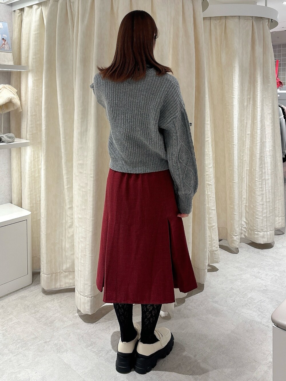 グレー系のニット/セーター、レッド系のスカート、ホワイト系のローファーを着用したレディースの秋コーディネートの2枚目の写真
