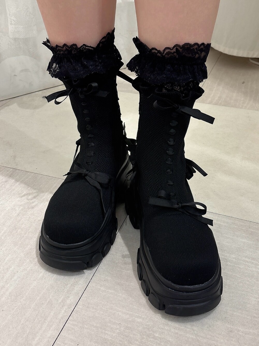 ブラウン系のスカート、ブラック系のブーツ、ホワイト系のカーディガン/ボレロを着用したレディースの秋コーディネートの7枚目の写真