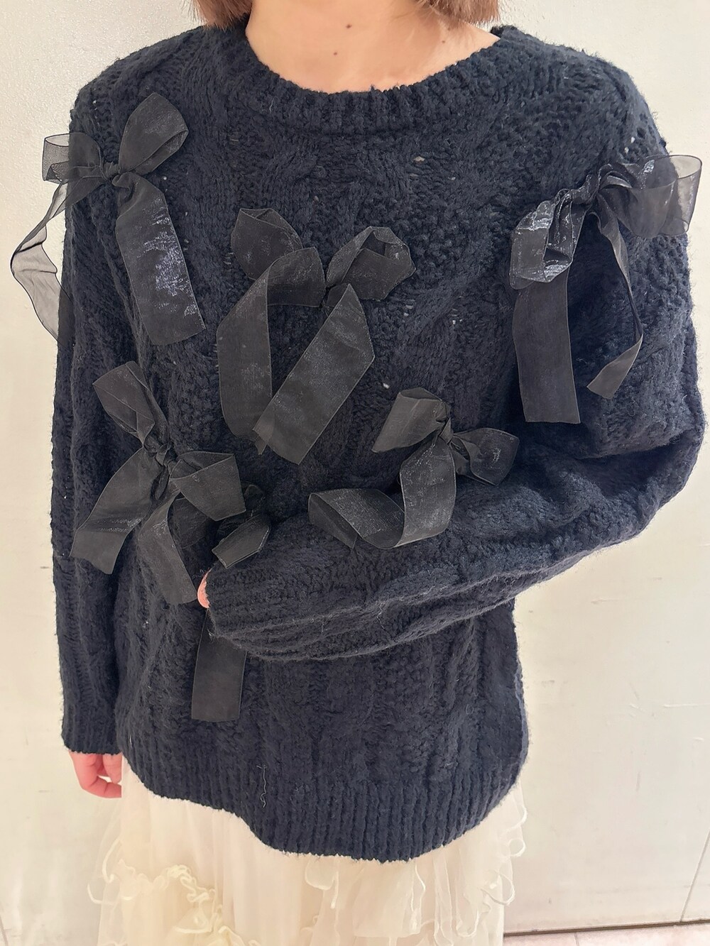 ブラック系のニット/セーター、レッド系のショルダーバッグ、ホワイト系のスカートを着用したレディースの冬コーディネートの6枚目の写真