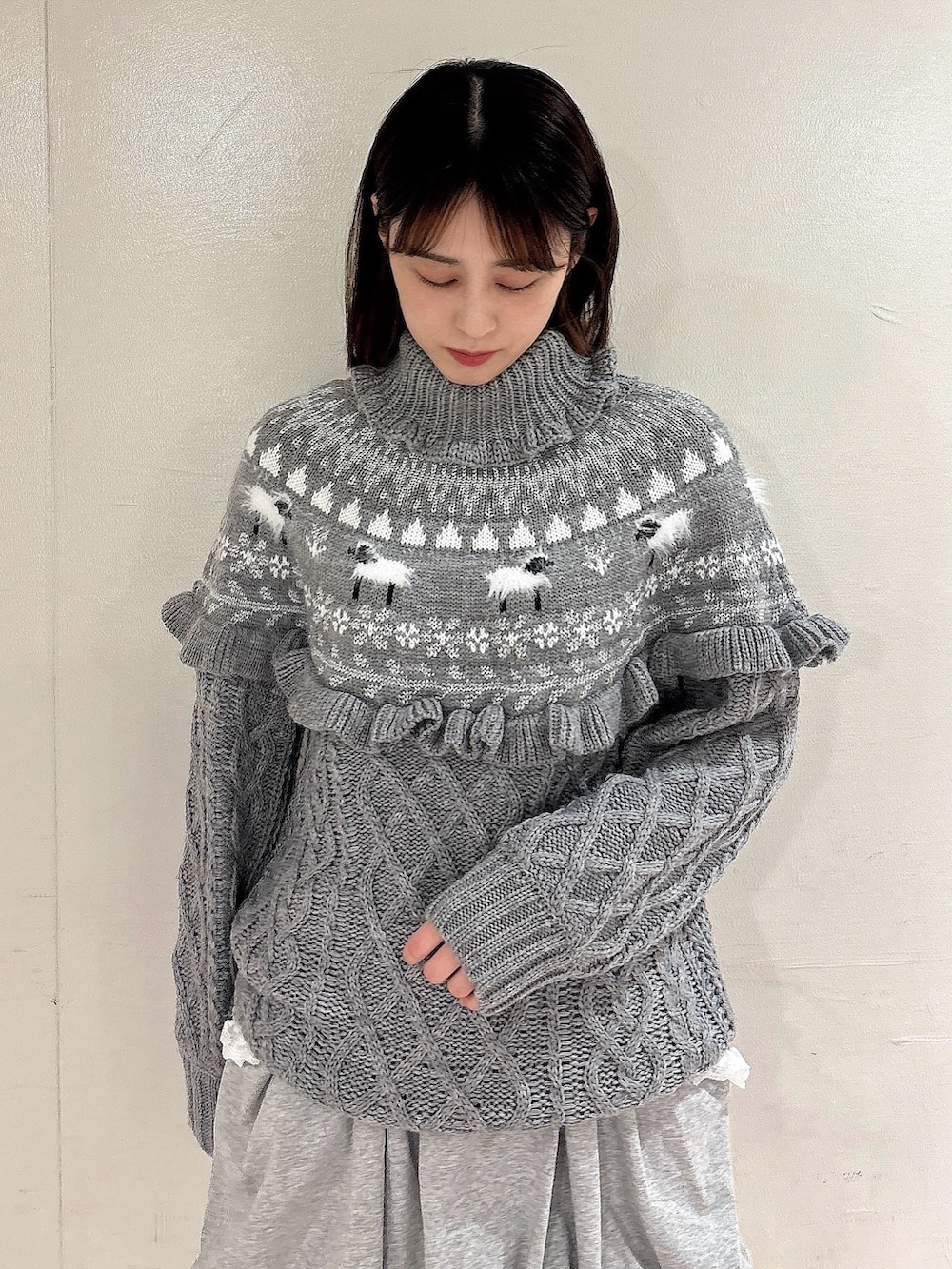 グレー系のニット/セーター、グレー系のスカート、ホワイト系のその他パンツを着用したレディースの冬コーディネートの3枚目の写真