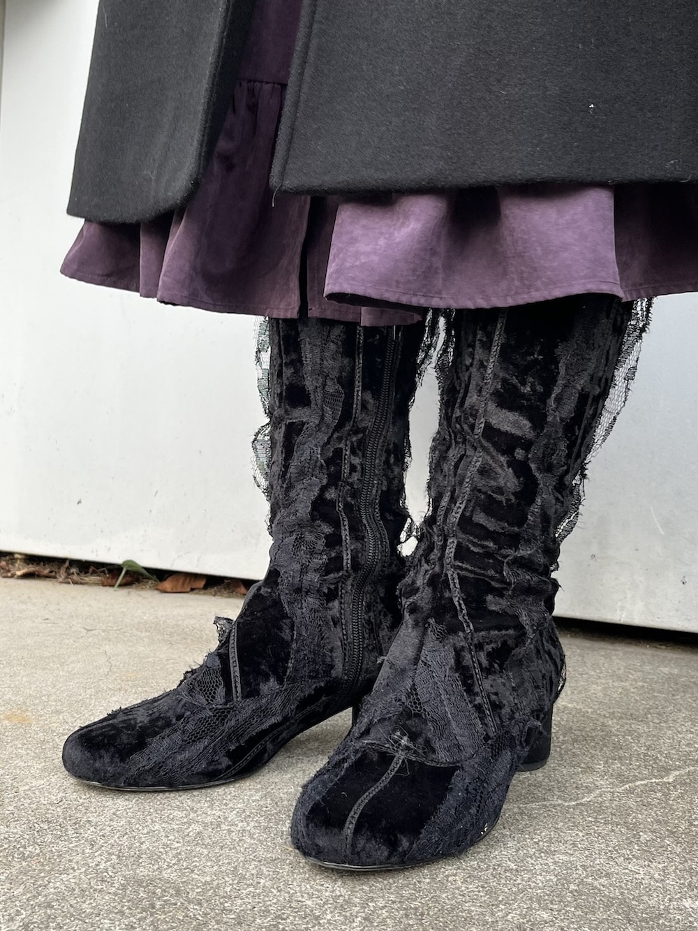 パープル系のワンピース、ブラック系のステンカラーコート、ブラック系のブーツを着用したレディースの冬コーディネートの3枚目の写真