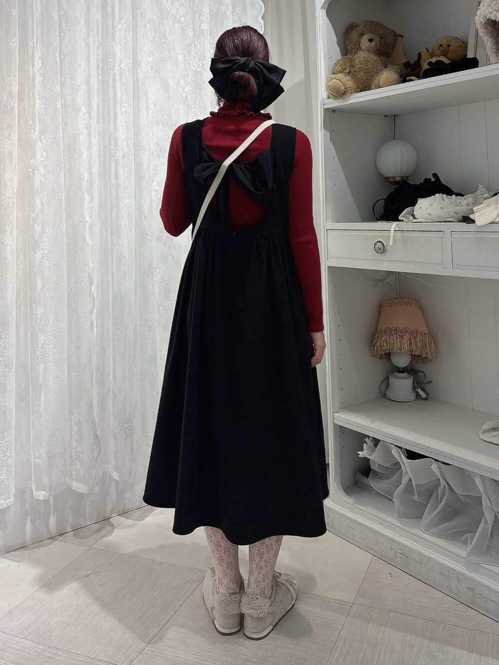 レッド系のニット/セーター、ベージュ系のショルダーバッグ、ブラック系のワンピースを着用したレディースの秋コーディネートの2枚目の写真