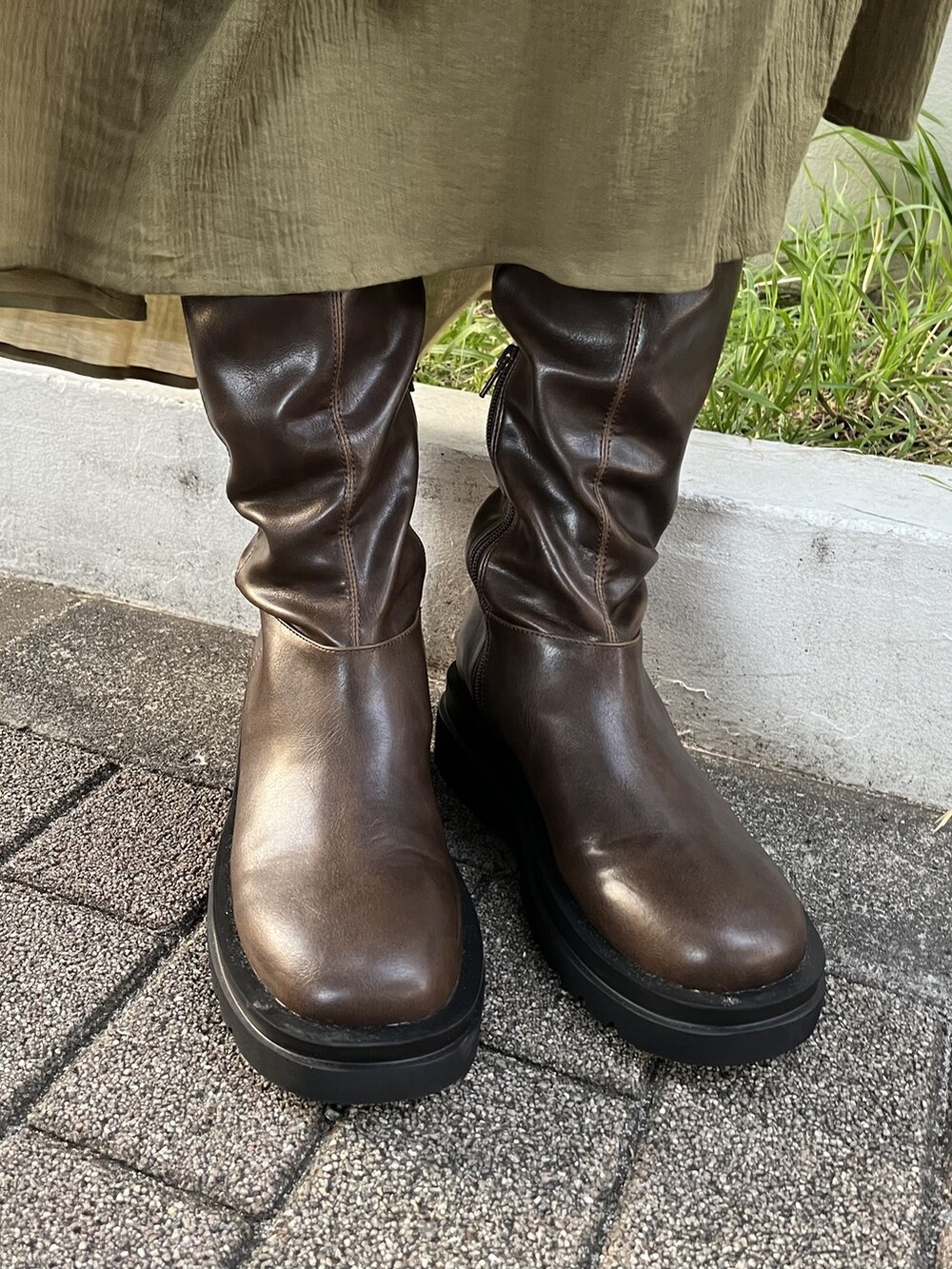 ブラック系のハンドバッグ、ホワイト系のニット/セーター、ブラウン系のブーツを着用したレディースの夏コーディネートの5枚目の写真