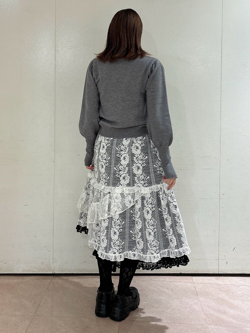 グレー系のニット/セーター、ブラック系のスカート、ホワイト系のスカートを着用したレディースの秋コーディネートの2枚目の写真