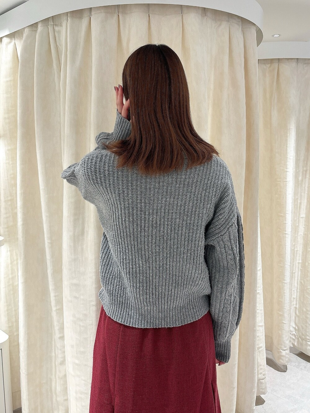 グレー系のニット/セーター、レッド系のスカート、ホワイト系のローファーを着用したレディースの秋コーディネートの4枚目の写真