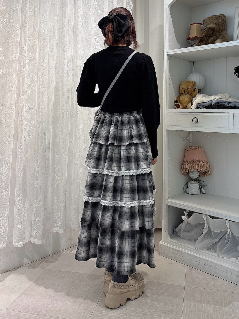 ブラック系のニット/セーター、ブラック系のスカート、グレー系のショルダーバッグを着用したレディースの秋コーディネートの2枚目の写真