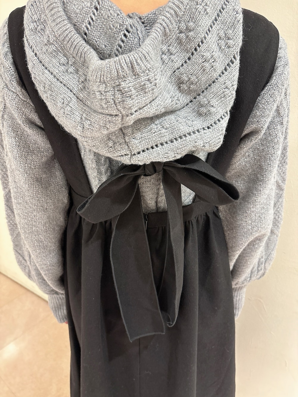 グレー系のニット/セーター、ブラック系のワンピース、ブラック系のブーツを着用したレディースの冬コーディネートの6枚目の写真