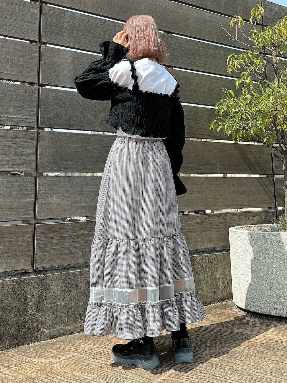 ブラック系のスカート、ホワイト系のTシャツ/カットソー、ブラック系のシャツ/ブラウスを着用したレディースの春コーディネートの2枚目の写真