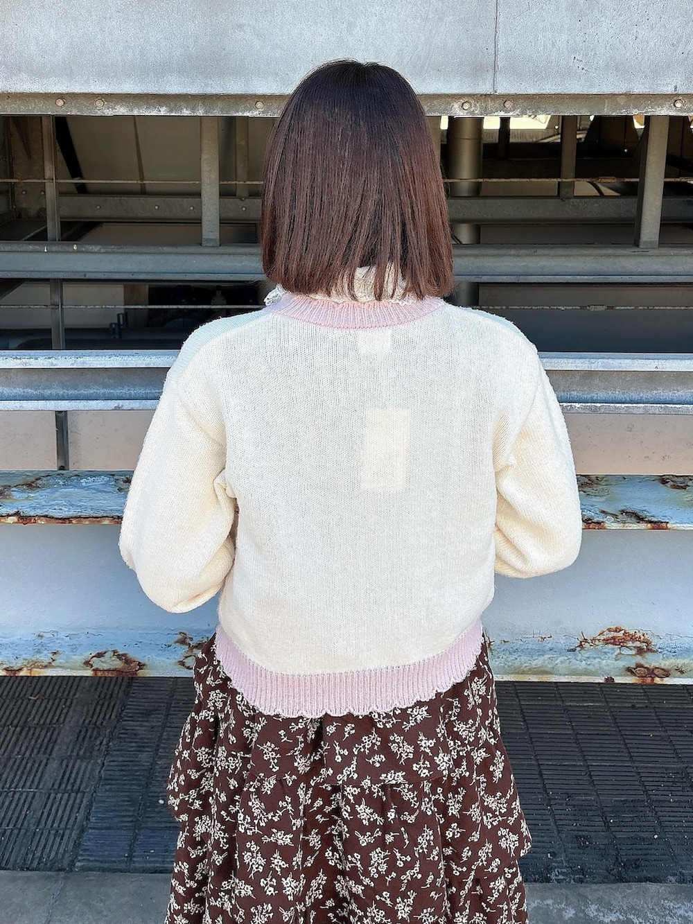 ブラウン系のワンピース、ブラック系のパンプス、ピンク系のカーディガン/ボレロを着用したレディースの冬コーディネートの7枚目の写真