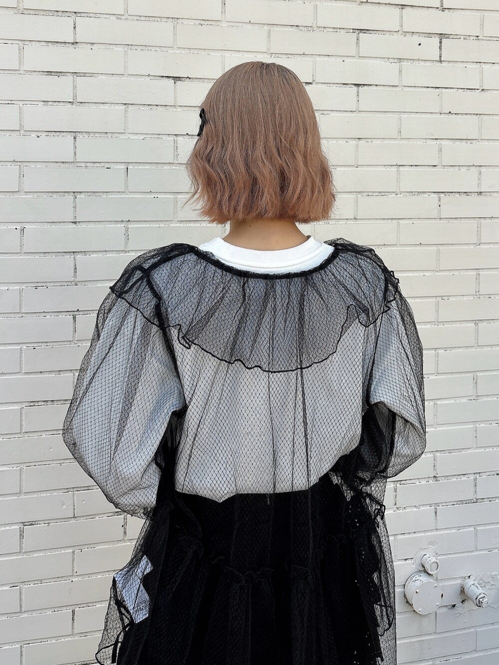 ブラック系のスカート、ブラック系のスニーカー、ホワイト系のTシャツ/カットソーを着用したレディースの春コーディネートの4枚目の写真