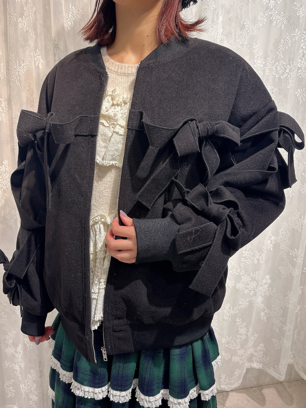 ブラック系のブルゾン、ホワイト系のニット/セーター、グリーン系のスカートを着用したレディースの秋コーディネートの5枚目の写真