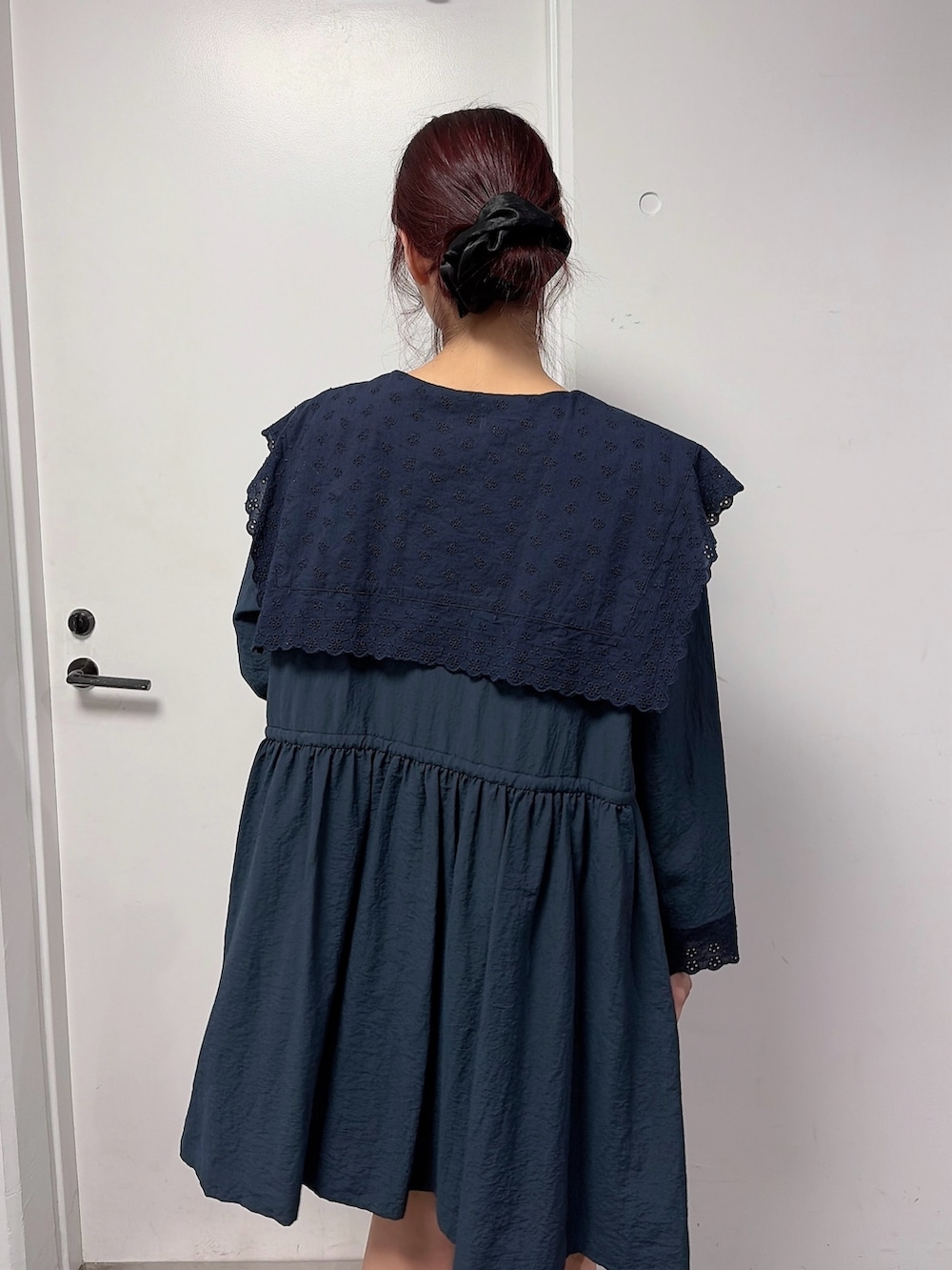 ブルー系のワンピース、ベージュ系のメッセンジャーバッグ、ブラック系のスニーカーを着用したレディースの冬コーディネートの4枚目の写真