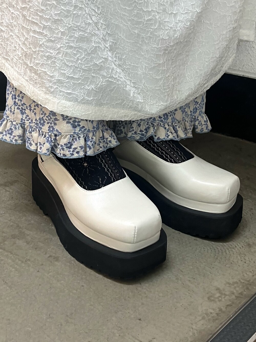 ホワイト系のワンピース、グレー系のニット/セーター、ブラック系のパンプスを着用したレディースの冬コーディネートの3枚目の写真