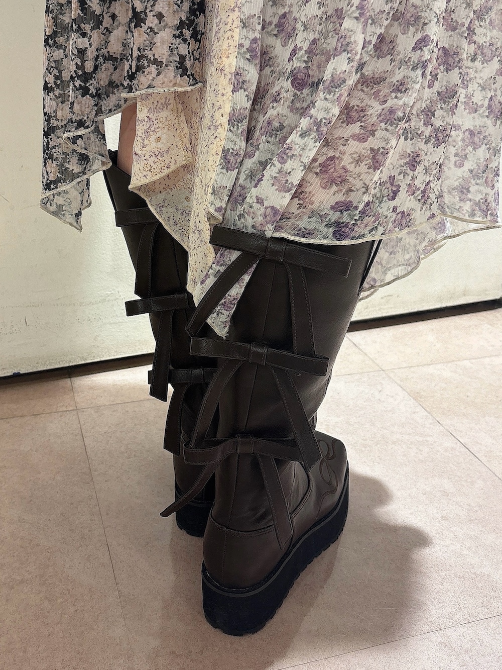 レッド系のスウェット、ブラック系のスカート、ブラウン系のブーツを着用したレディースの秋コーディネートの8枚目の写真