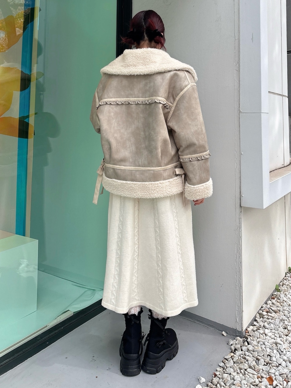 ベージュ系のムートンコート、ホワイト系のワンピース、ブラック系のブーツを着用したレディースの秋コーディネートの2枚目の写真