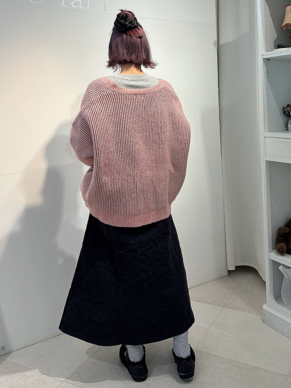 ピンク系のカーディガン/ボレロ、ブラック系のスカート、ブラック系のスニーカーを着用したレディースの冬コーディネートの2枚目の写真