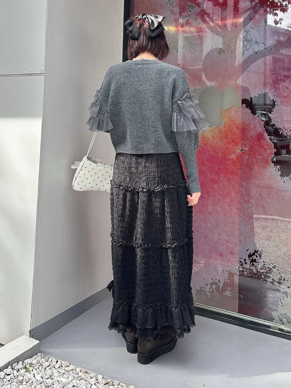 グレー系のニット/セーター、ブラック系のスカート、その他のハンドバッグを着用したレディースの夏コーディネートの2枚目の写真