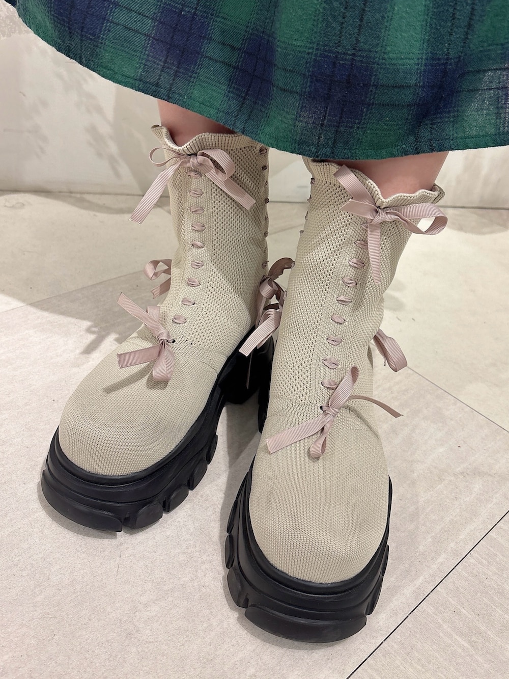 ブラック系のブルゾン、ホワイト系のニット/セーター、グリーン系のスカートを着用したレディースの秋コーディネートの7枚目の写真