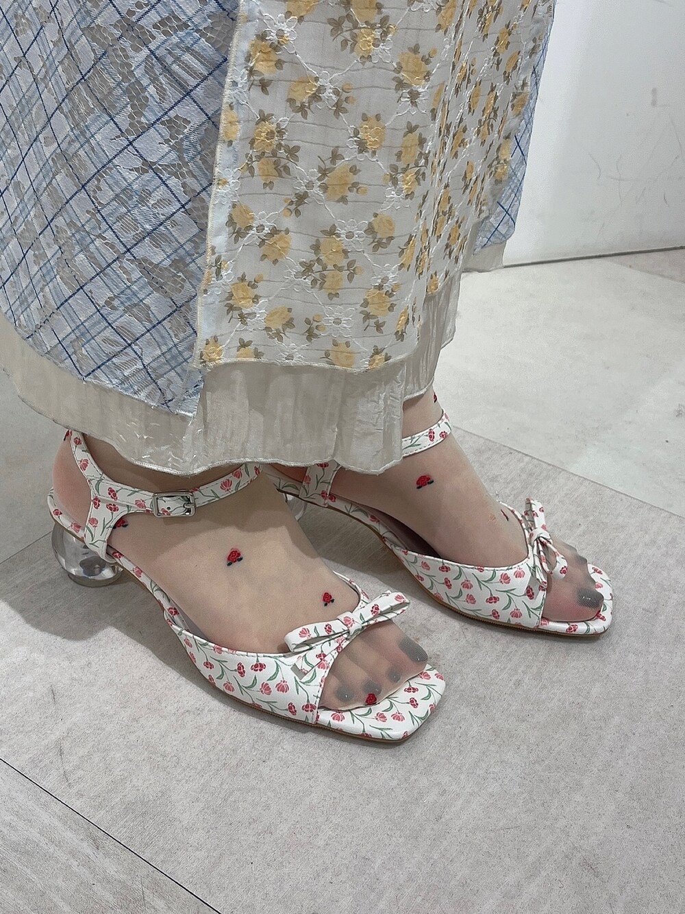 ホワイト系のパンプス、イエロー系のワンピース、ブルー系のキャミソールを着用したレディースの春コーディネートの3枚目の写真