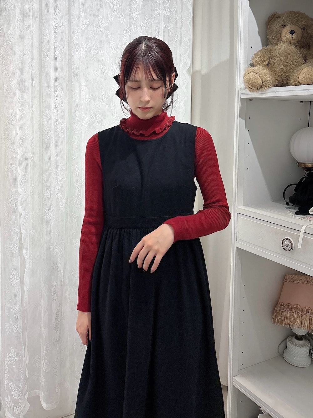 レッド系のニット/セーター、ベージュ系のショルダーバッグ、ブラック系のワンピースを着用したレディースの秋コーディネートの3枚目の写真