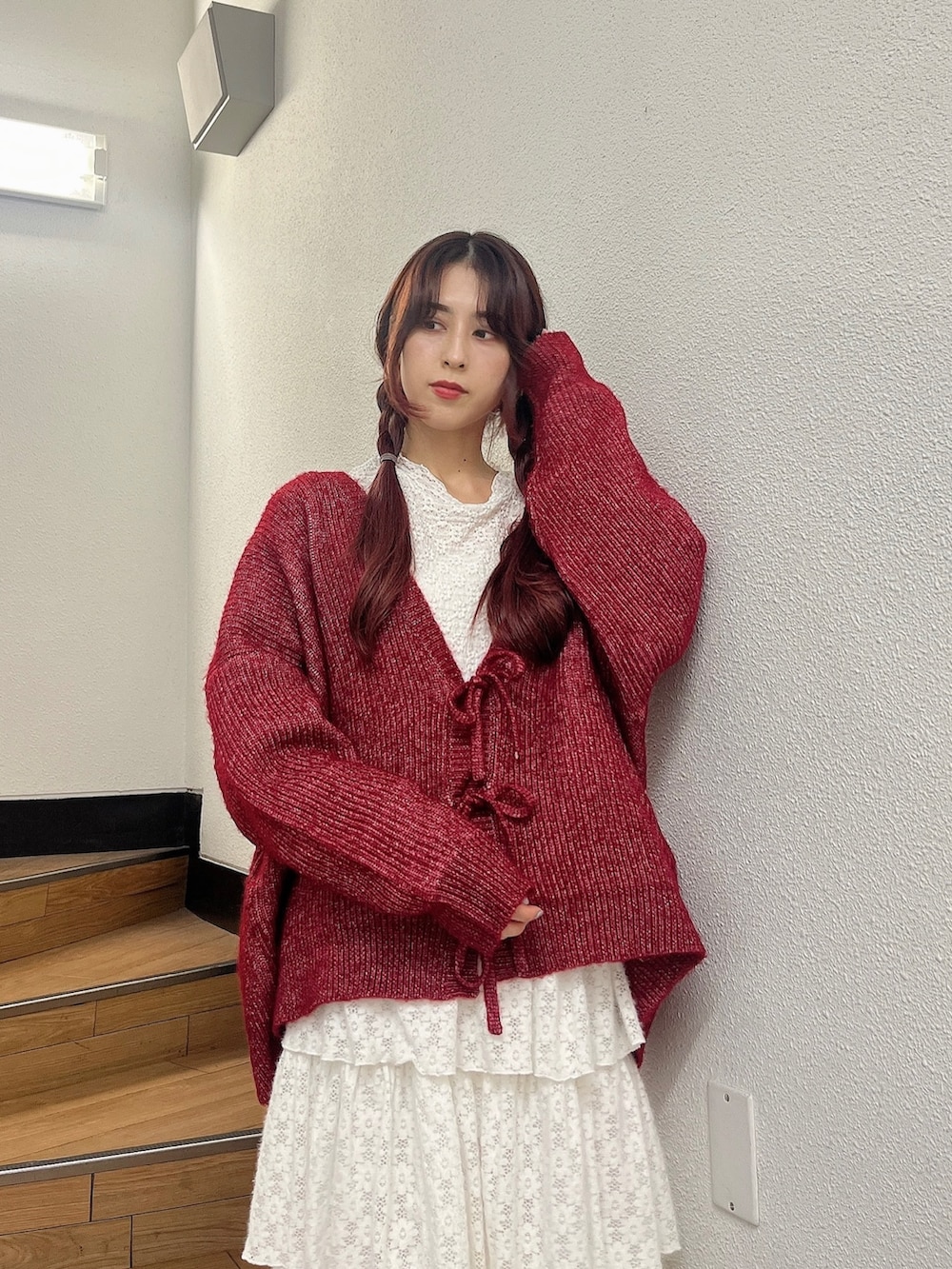 レッド系のカーディガン/ボレロ、ホワイト系のスカート、ベージュ系のスリッポンを着用したレディースの秋コーディネートの2枚目の写真