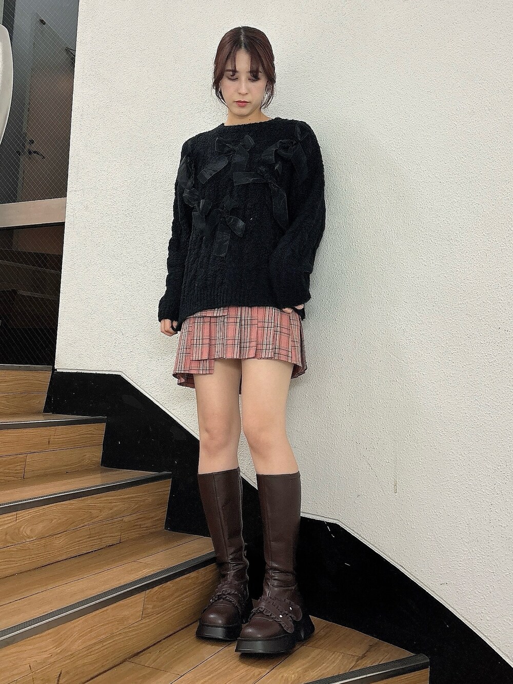 ピンク系のスカート、ブラウン系のブーツ、ブラック系のダウンジャケット/コートを着用したレディースの冬コーディネートの4枚目の写真