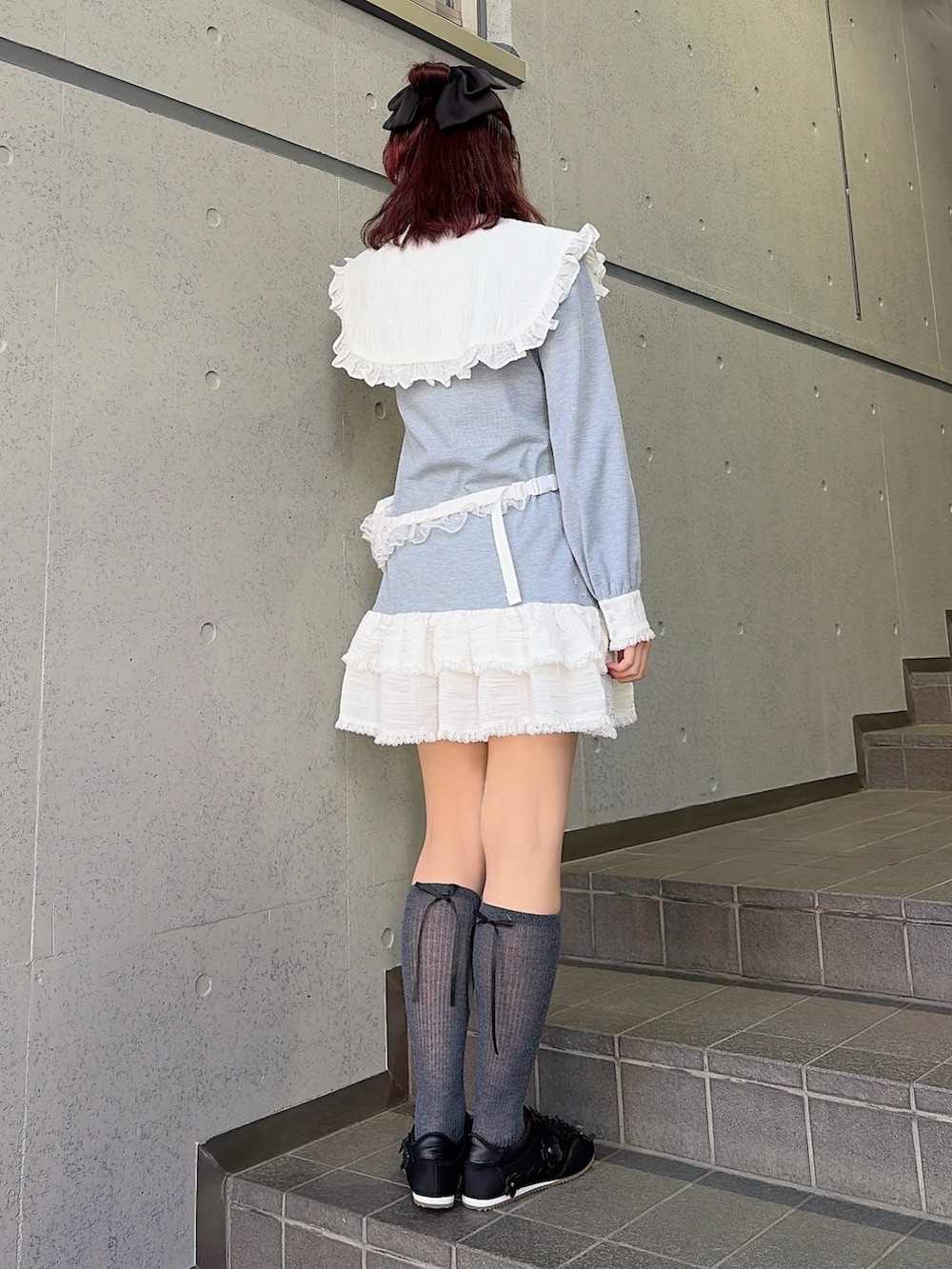 グレー系のワンピース、ブラック系のスニーカー、ホワイト系のボディバッグ/ウエストポーチを着用したレディースの冬コーディネートの2枚目の写真