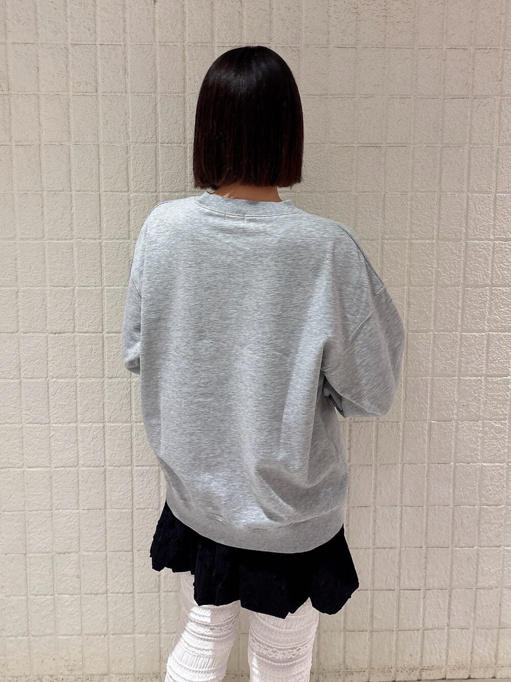 グレー系のスウェット、ブラック系のスカート、ホワイト系のその他パンツを着用したレディースの冬コーディネートの4枚目の写真