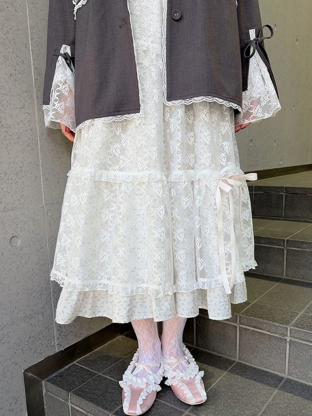 グレー系のテーラードジャケット、ホワイト系のワンピース、ホワイト系のスカートを着用したレディースの冬コーディネートの6枚目の写真