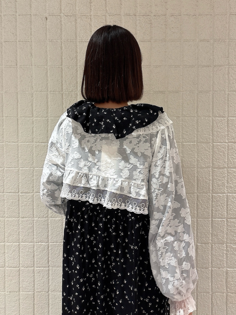 ブラック系のワンピース、ホワイト系のカーディガン/ボレロ、ブラック系のスニーカーを着用したレディースの冬コーディネートの4枚目の写真