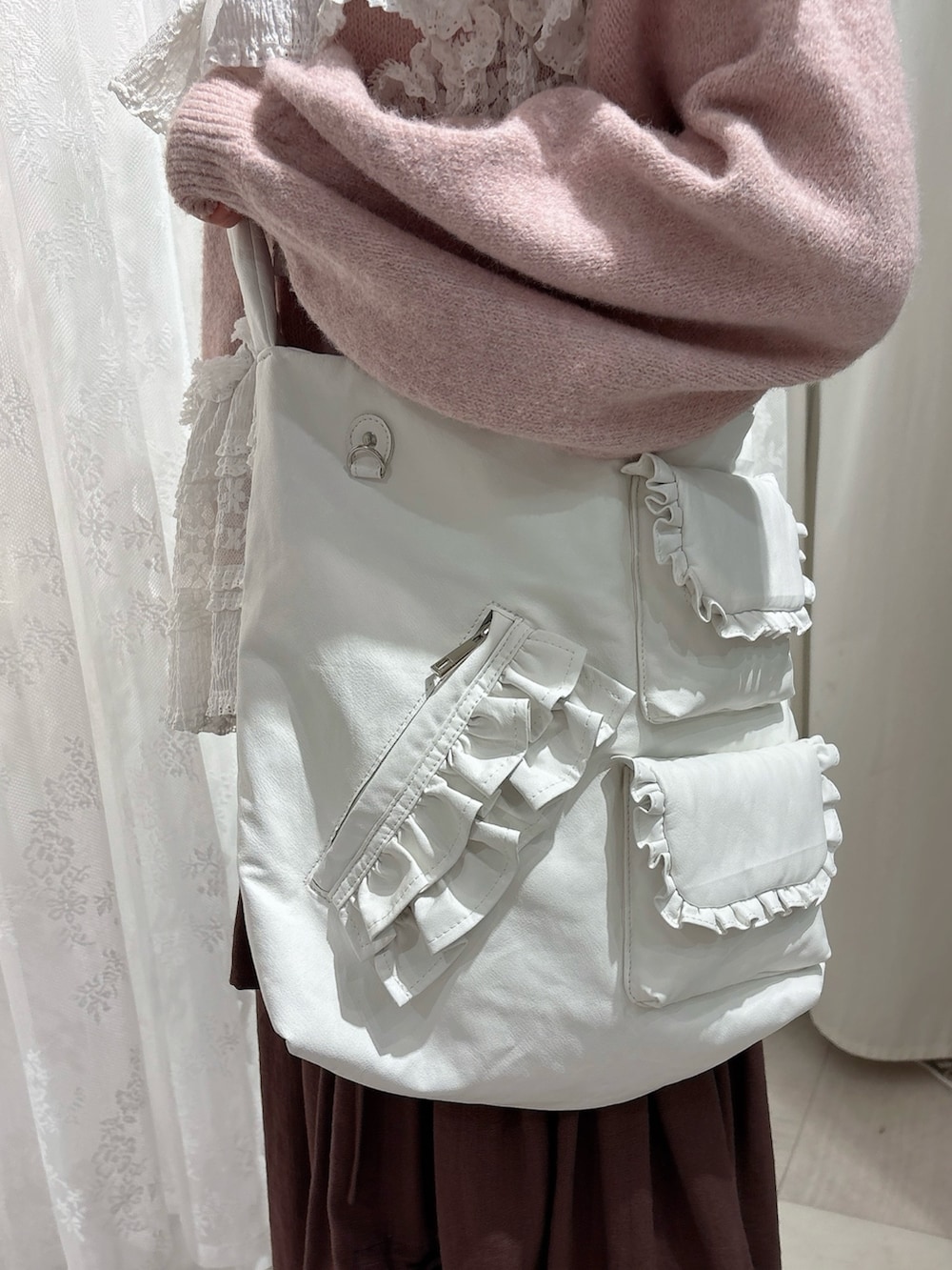 ピンク系のニット/セーター、ホワイト系のショルダーバッグ、ブラウン系のスカートを着用したレディースの秋コーディネートの7枚目の写真