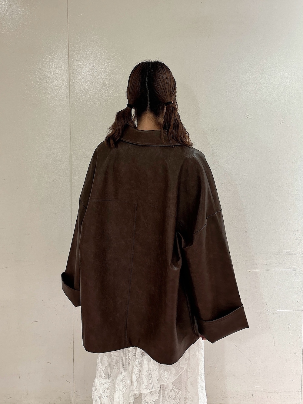 ブラウン系のブルゾン、ブラウン系のニット/セーター、ホワイト系のスカートを着用したレディースの秋コーディネートの4枚目の写真