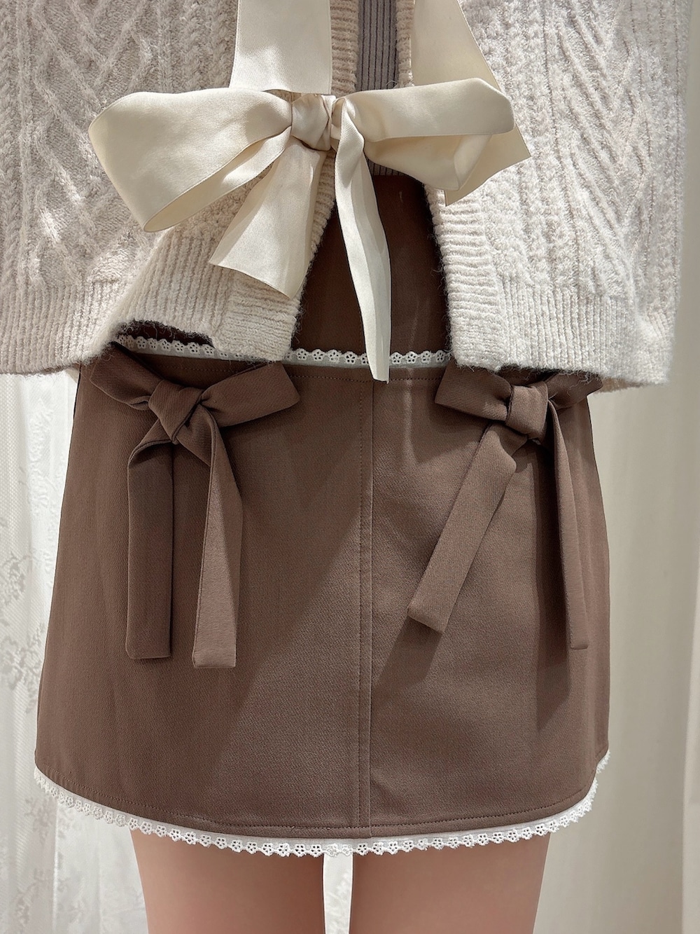 ブラウン系のスカート、ブラック系のブーツ、ホワイト系のカーディガン/ボレロを着用したレディースの秋コーディネートの6枚目の写真